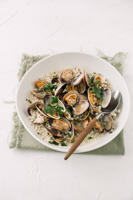 Overhead food photography of clams in a white bowl on white background.