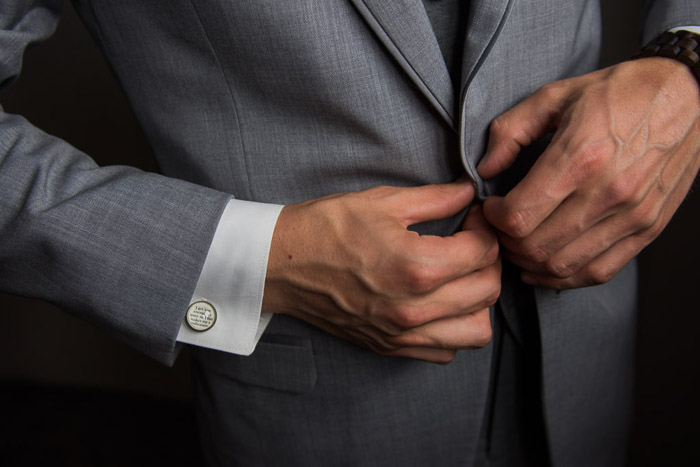 A closeup wedding portrait of the groom buttoning his jacket