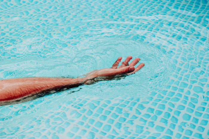 A persons hand spread out in water using orange and blue color scheme