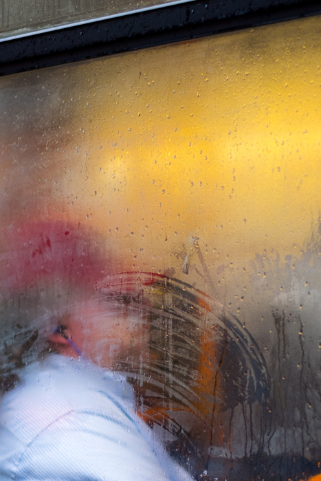 A portrait of a person shot through a rain splashed window