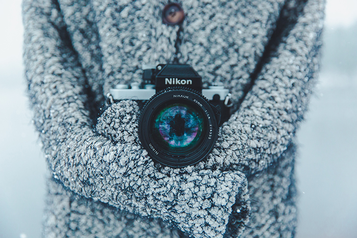 A close up of a Nikon camera around the neck of a photographer, shooting snow portraits
