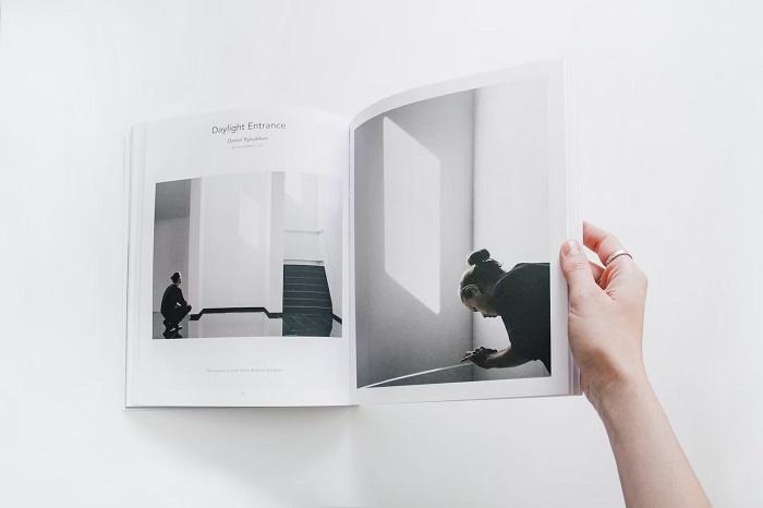 Overhead shot of a hand flipping through a magazine on a white table