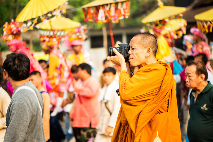 A buddhist monk taking photos with a DSLR outdoors among crowds - how to start a camera club