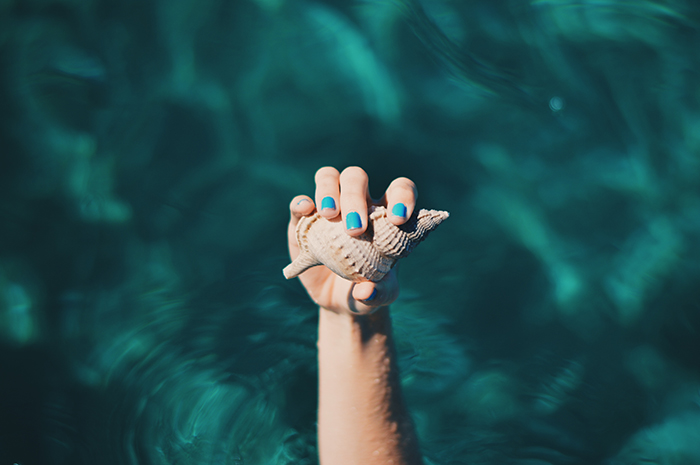 cool nail photography of a female model with painted nails holding a seashell