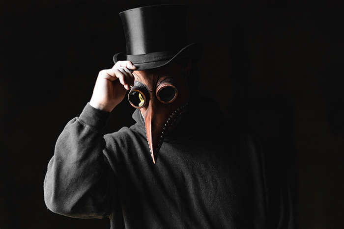 A person in a scary mask in front of a black background