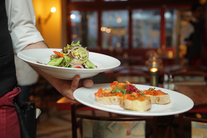 A waiter holding plates of delicious food in a restaurant