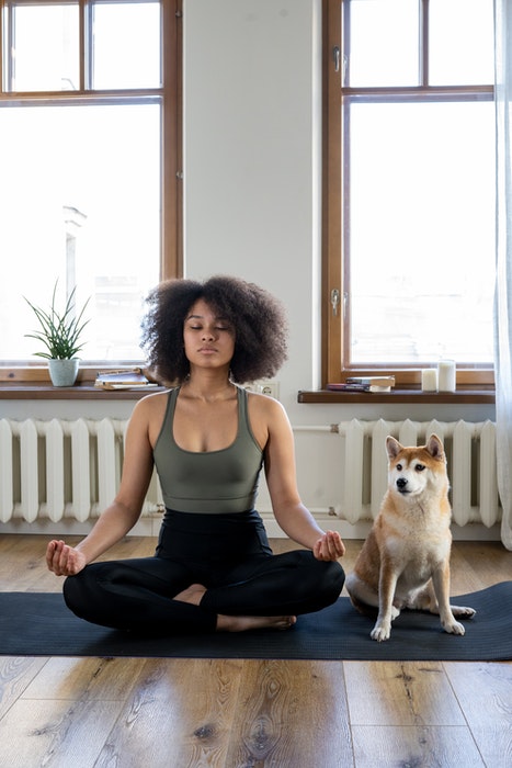 A girl doing yoga beside her cute dog as an example of family photos with pets
