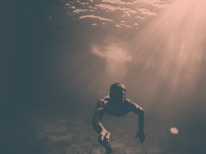 Diver taking a selfie while swimming underwater using a GoPro