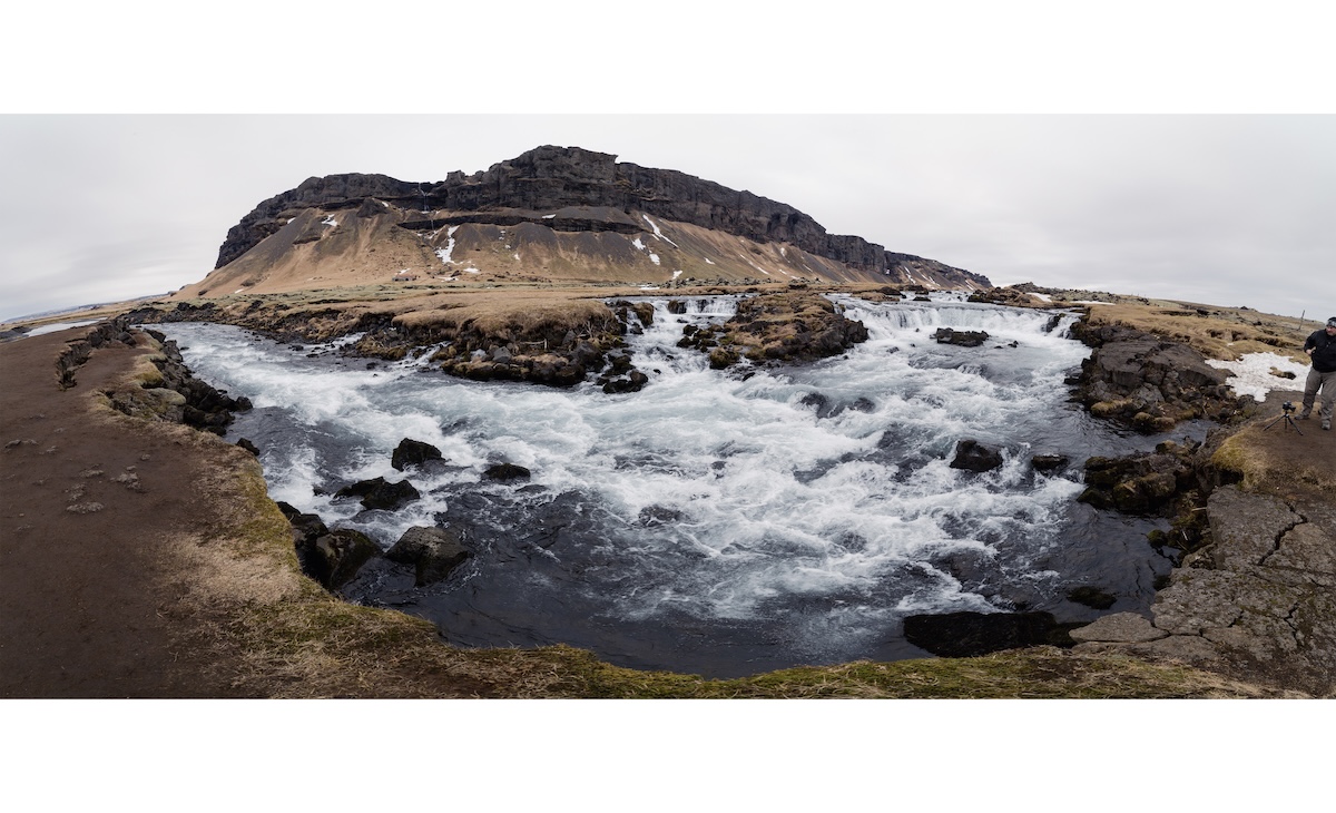 A panorama of a river with a mountain in the background
